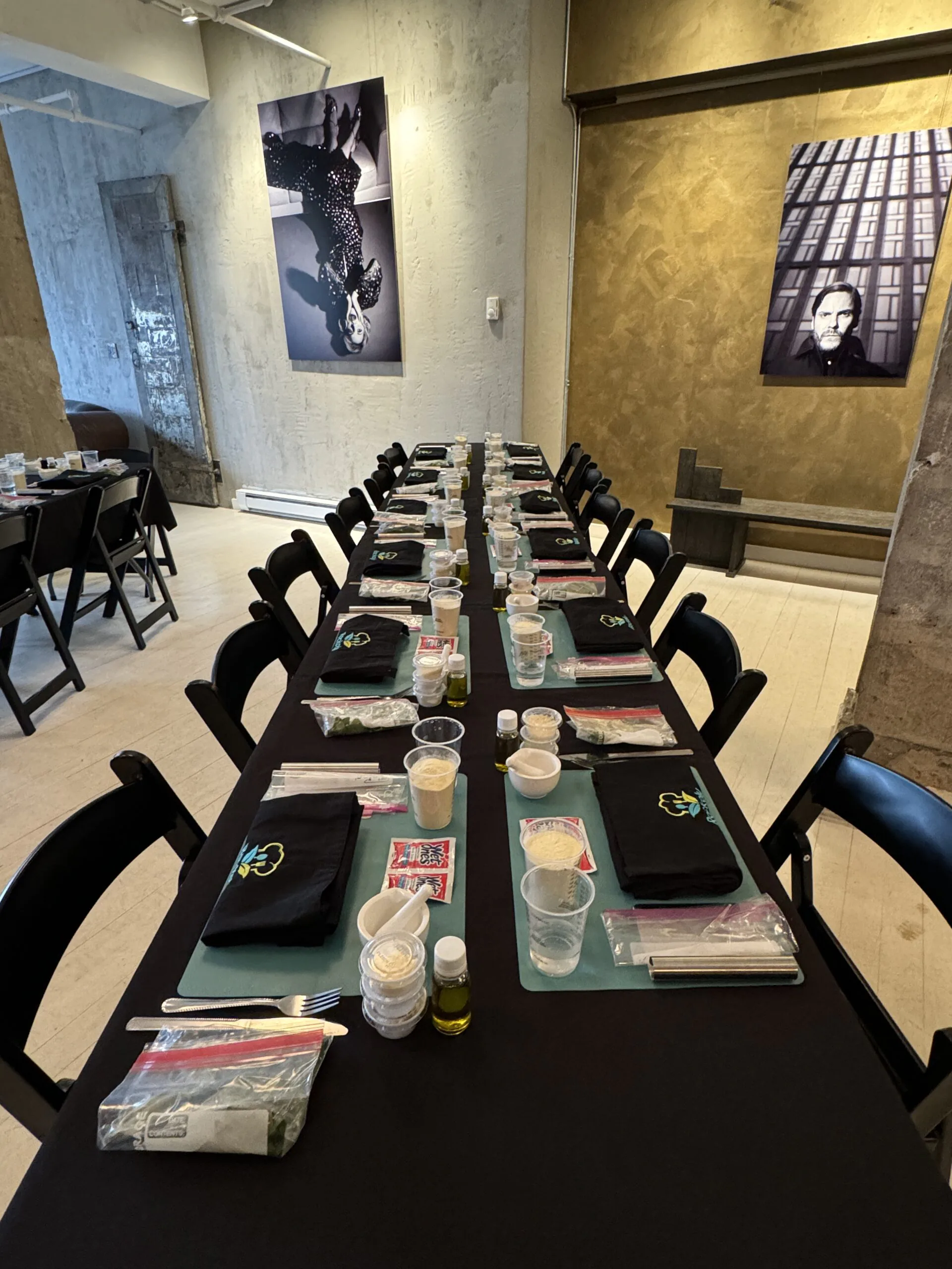 Long banquet table set with individual cooking stations, aprons, cups and place mats before an event