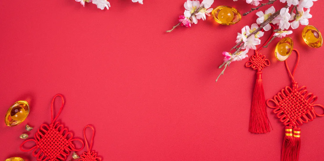 Red Lunar New Year backdrop with plum blossom branches, gold ingots and tasselled Chinese knots