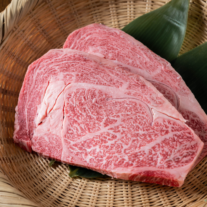 Thick slices of raw Japanese Wagyu ribeye with heavy marbling resting in a bamboo basket