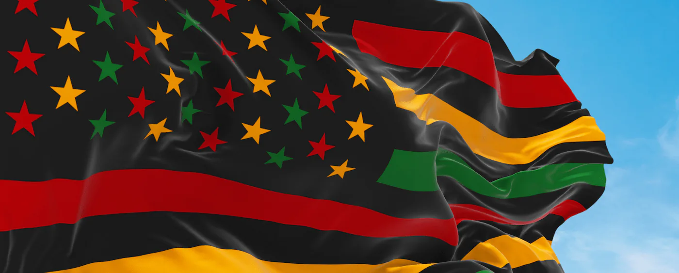 American flag rendered in the Pan-African colors of black, red, green and gold waving against blue sky