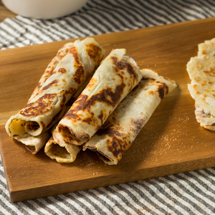 Rolled Nordic lefse flatbreads dusted with cinnamon sugar on a wooden board