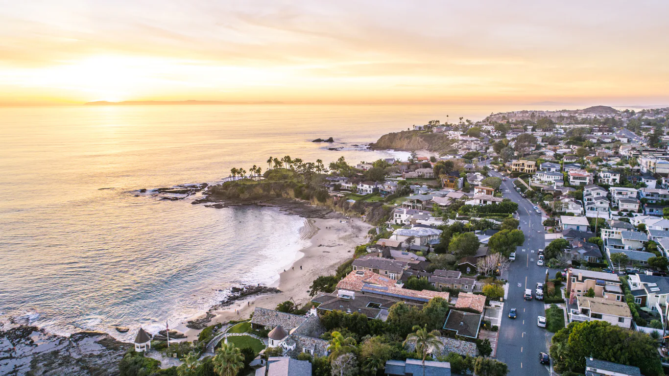Aerial view of a Southern California beach town and rocky cove at sunset over the Pacific