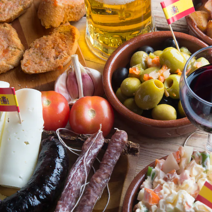 Spanish tapas spread with marinated olives, cured chorizo, cheese, tomato bread and a glass of beer