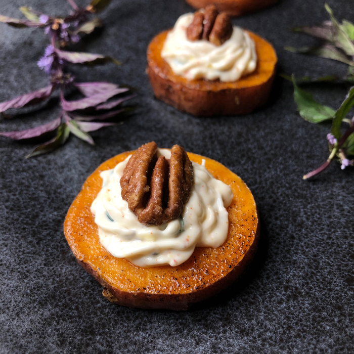 Roasted sweet potato rounds topped with piped whipped goat cheese and toasted pecans