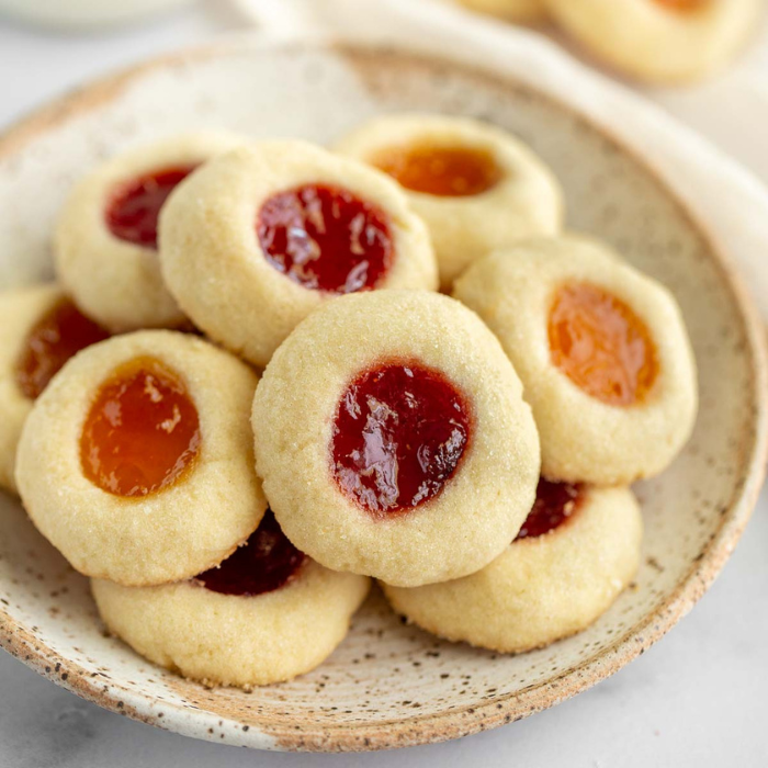 Plate of shortbread thumbprint cookies filled with raspberry and apricot preserves