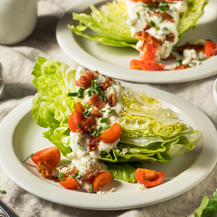 Iceberg wedge salad topped with bacon, blue cheese, creamy dressing, tomatoes and chives