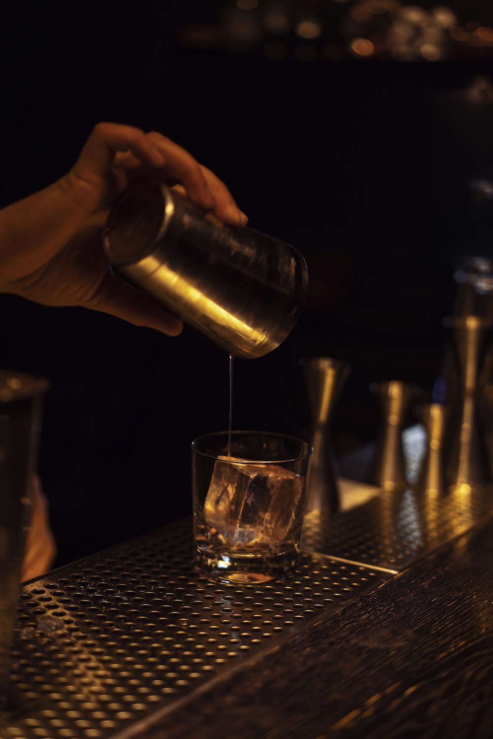 Cocktail shaker pouring into a glass during mixology class